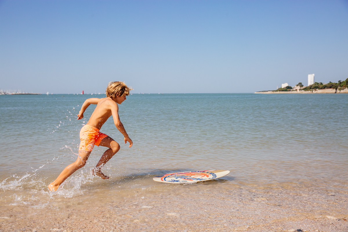 enfant faisant du skim board sur la plage
