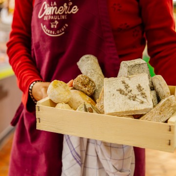 Fromagère tenant dans ses bras une cagette de fromages