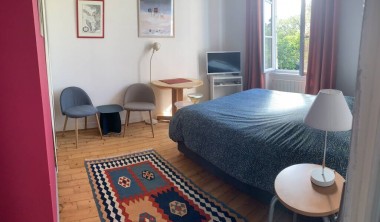 Chambre avec lit double, petite télévision, fenêtre donnant sur les arbres du jardin. Chambre - La Villa Andrée
