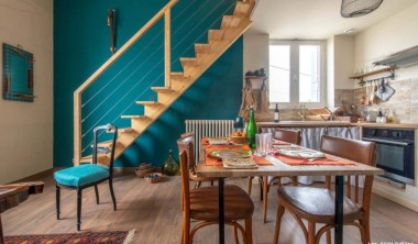 Espace salon-cuisine avec table et 4 chaises, cuisine tut équipée, escalier mnant à l'étage. Décoration colorée et soignée Salon - cuisine - Les Ecologites